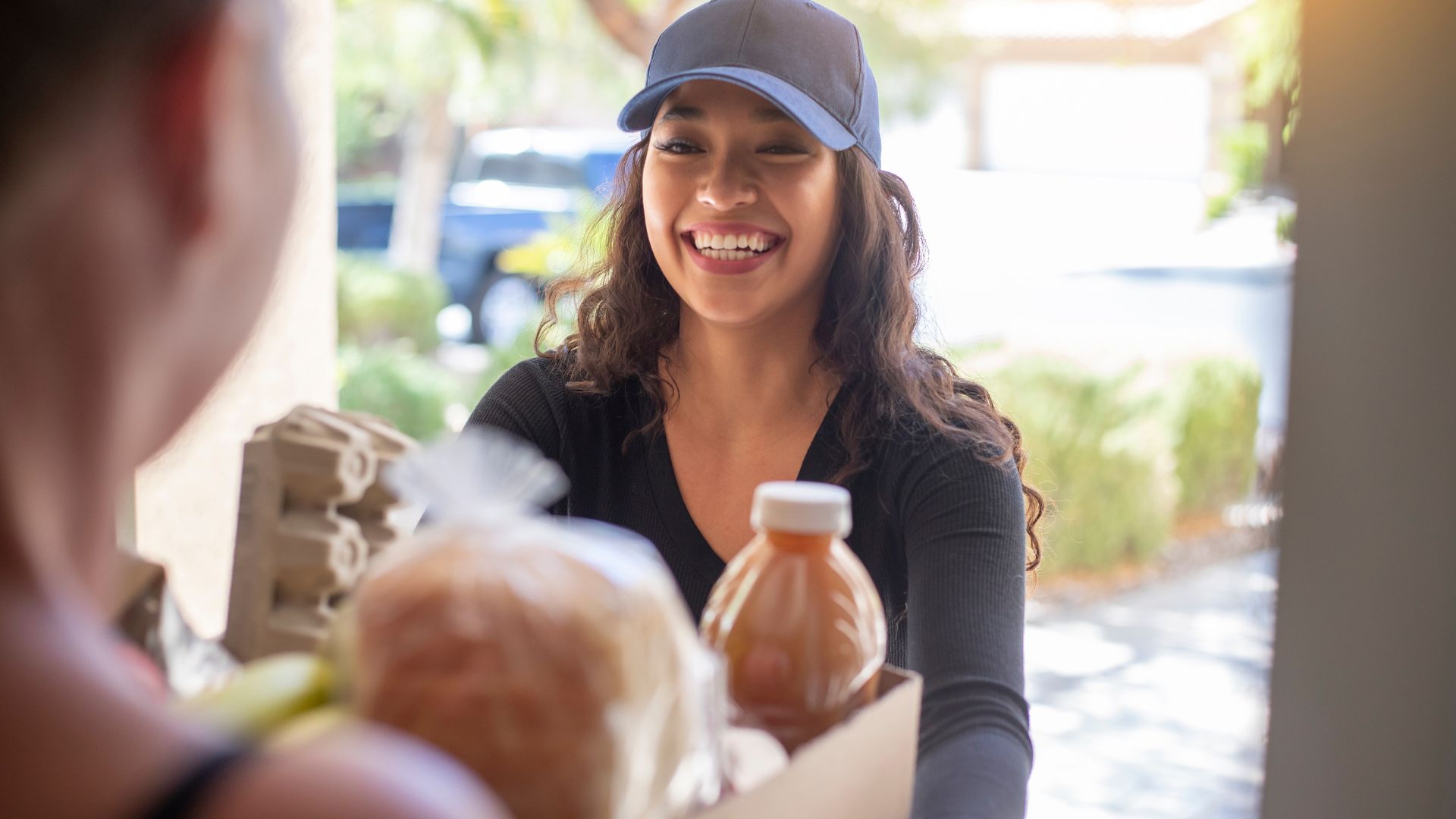 Smiling delivery person handing over food and drink package