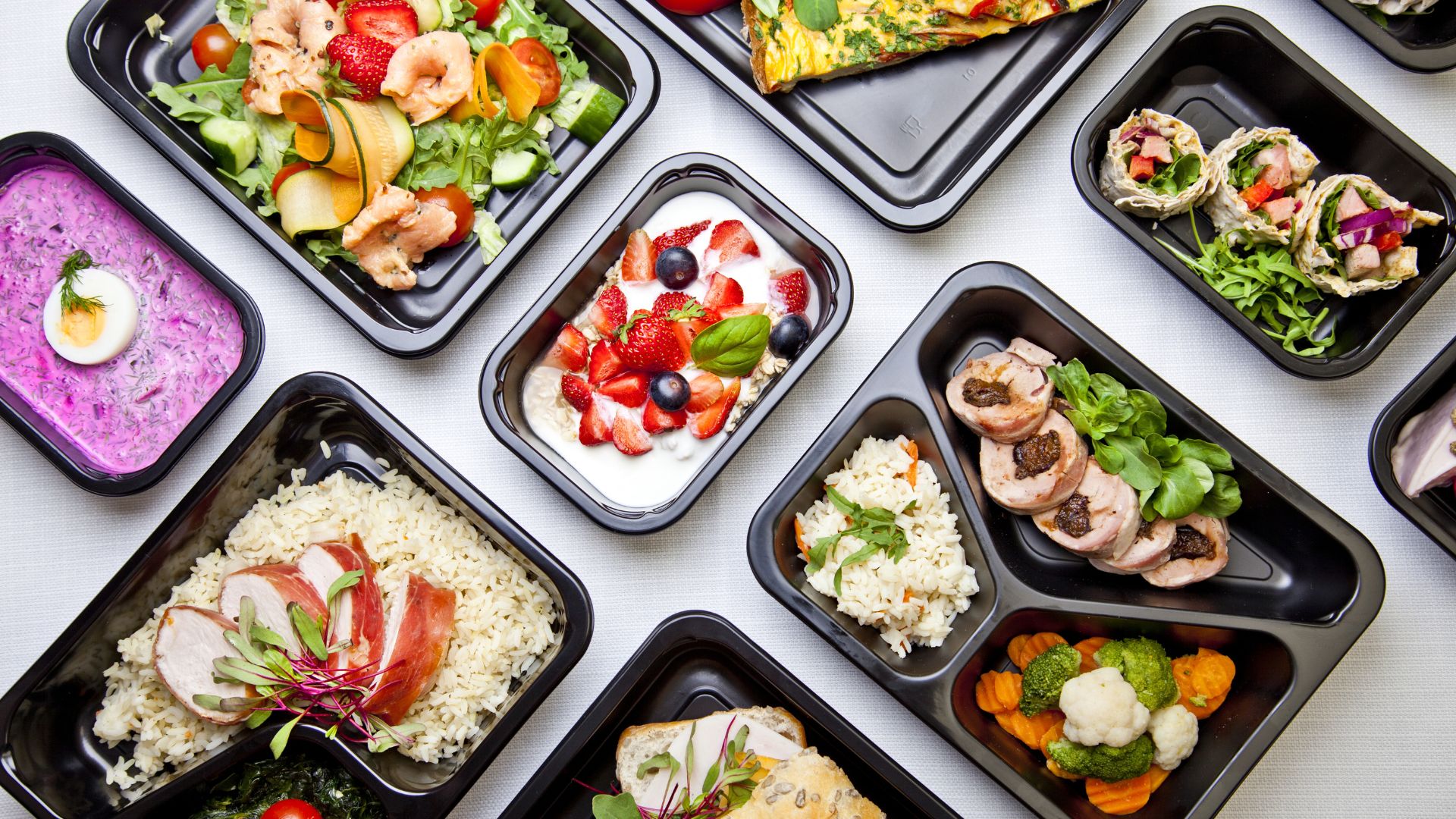 Variety of gourmet meal prep dishes in black containers